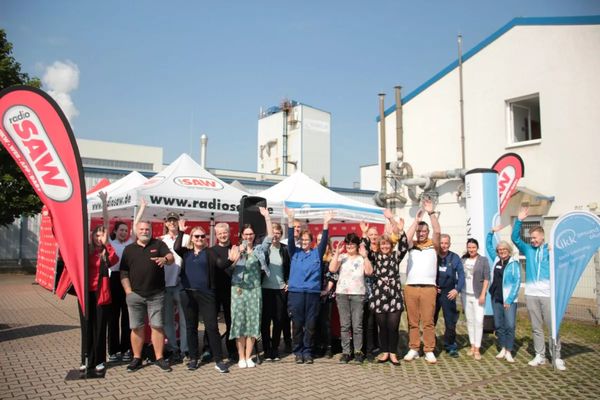 Belegschaft der Eurecat Deutschland GmbH winkt vor dem Stand von Radio SAW auf dem Werksgelände